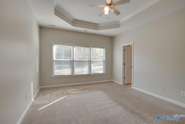 unfurnished room featuring ornamental molding, light colored carpet, ceiling fan, and a raised ceiling