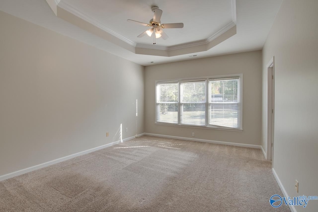 unfurnished room with a tray ceiling, light colored carpet, ceiling fan, and crown molding