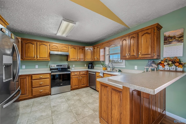 kitchen featuring appliances with stainless steel finishes, a textured ceiling, light tile patterned floors, sink, and kitchen peninsula