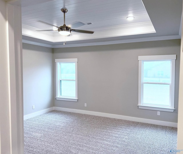 carpeted spare room featuring crown molding, ceiling fan, and a raised ceiling