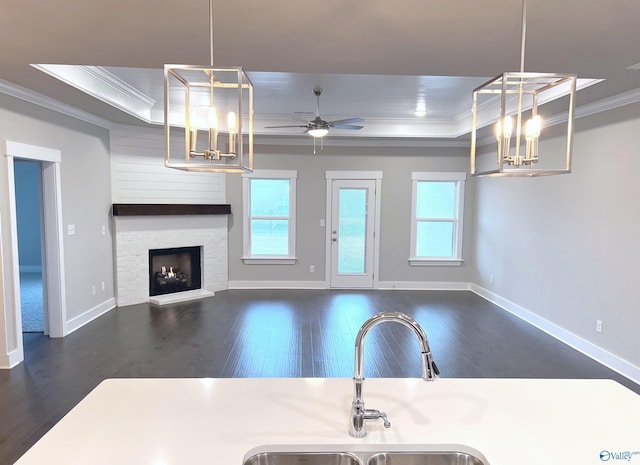 kitchen featuring ceiling fan, hanging light fixtures, dark hardwood / wood-style floors, a tray ceiling, and ornamental molding