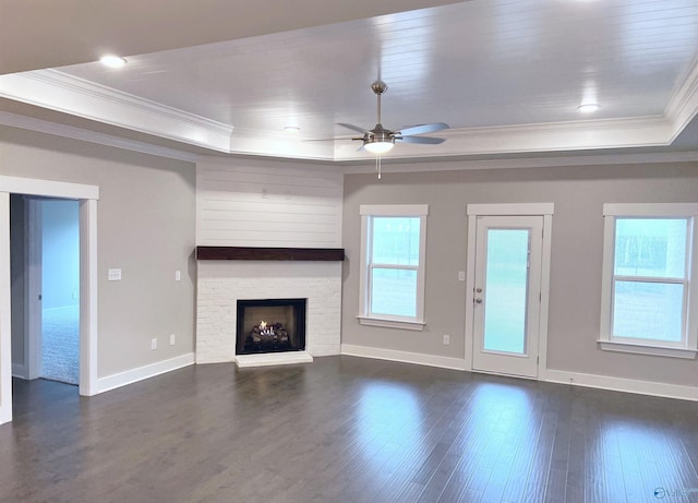 unfurnished living room with crown molding, dark hardwood / wood-style floors, a tray ceiling, and ceiling fan