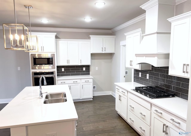 kitchen with stainless steel appliances, sink, hanging light fixtures, and a center island with sink