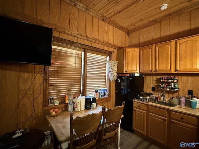 kitchen featuring wooden walls, dark wood-style flooring, a sink, wood ceiling, and freestanding refrigerator