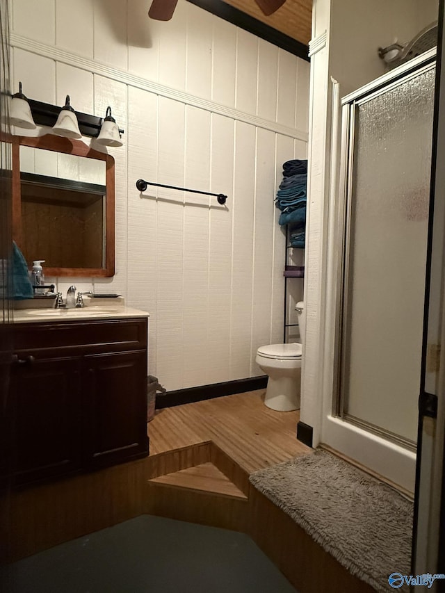 full bath with a stall shower, vanity, toilet, and wood finished floors