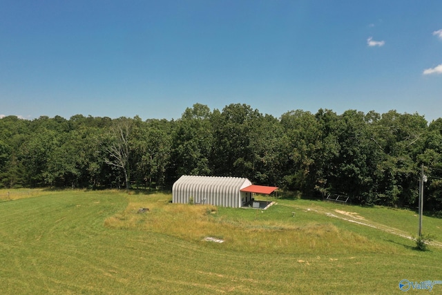 view of yard featuring an outbuilding, a forest view, and an outdoor structure