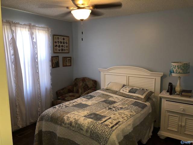 bedroom featuring ceiling fan, visible vents, and a textured ceiling