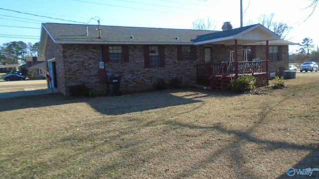 back of property featuring brick siding, a yard, a chimney, and a wooden deck