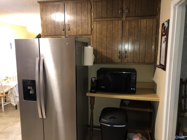 kitchen with black microwave, stainless steel refrigerator with ice dispenser, and light countertops