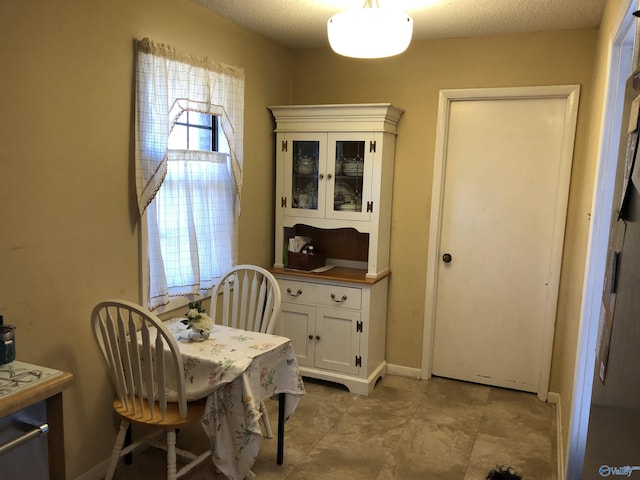 dining area featuring a textured ceiling and baseboards