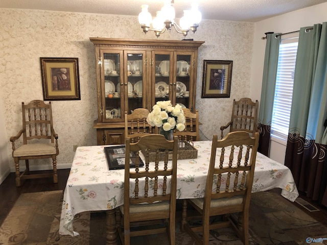 dining area featuring dark wood-style floors, a notable chandelier, a textured ceiling, baseboards, and wallpapered walls