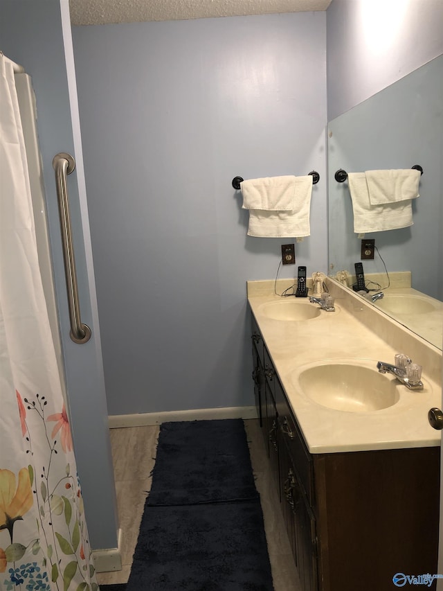 full bath with double vanity, baseboards, and a sink