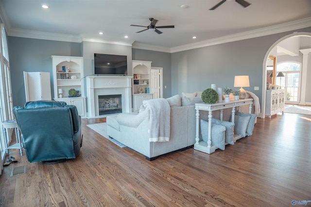 living room featuring ornamental molding, dark hardwood / wood-style flooring, built in shelves, and ceiling fan