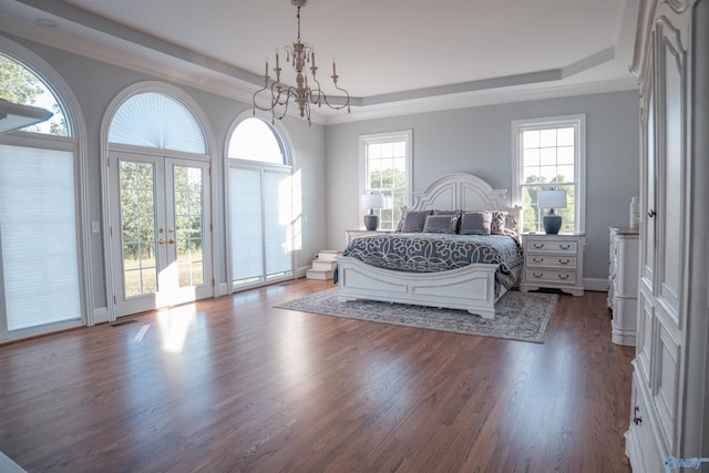 bedroom featuring a tray ceiling, dark hardwood / wood-style flooring, multiple windows, and an inviting chandelier