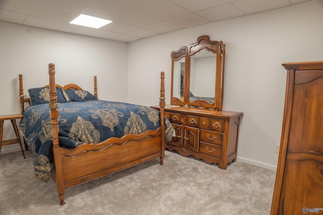 bedroom with a drop ceiling and light colored carpet