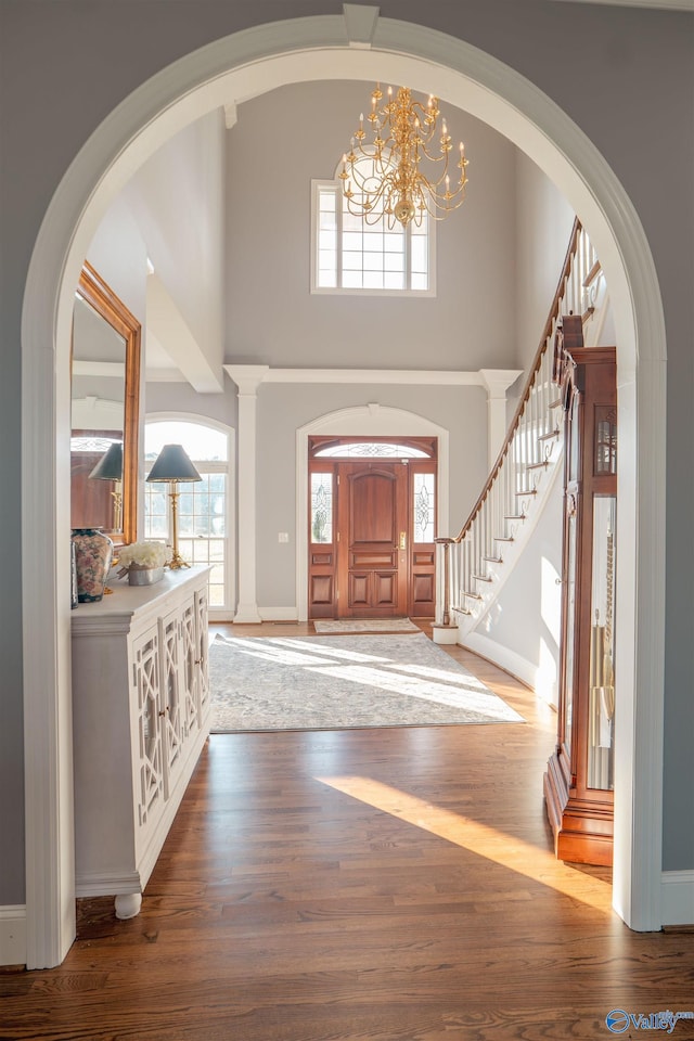 foyer entrance with a chandelier, hardwood / wood-style flooring, and a towering ceiling