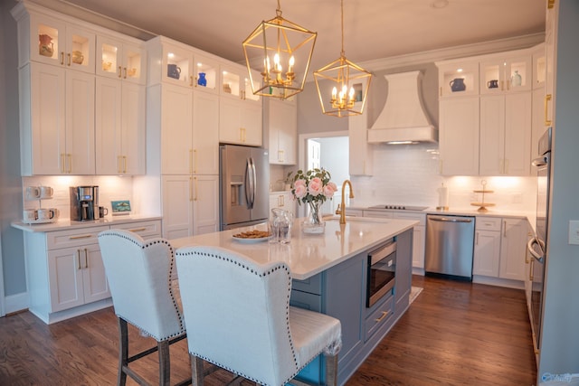 kitchen featuring dark hardwood / wood-style floors, stainless steel appliances, custom range hood, and a kitchen island with sink