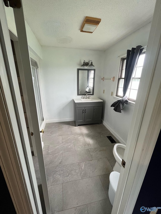 full bath with baseboards, vanity, toilet, and a textured ceiling