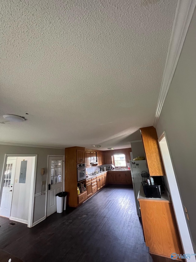 kitchen with ornamental molding, stainless steel oven, brown cabinets, and a textured ceiling