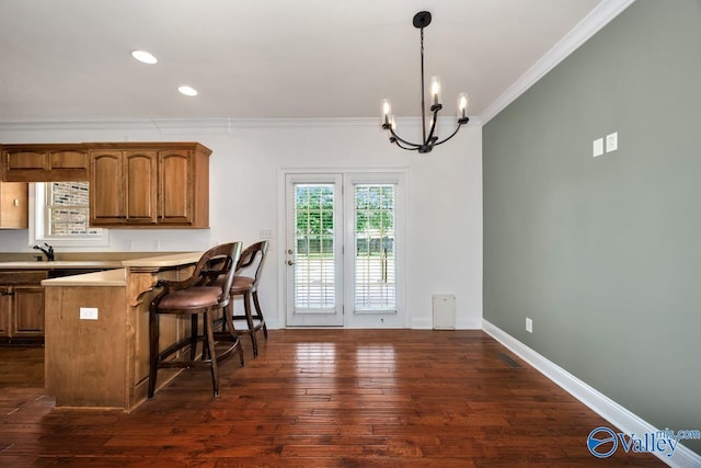 105 Patdean Dr, Huntsville, AL 35811 - kitchen with ornamental molding, a chandelier, a kitchen bar, light countertops, and brown cabinetry