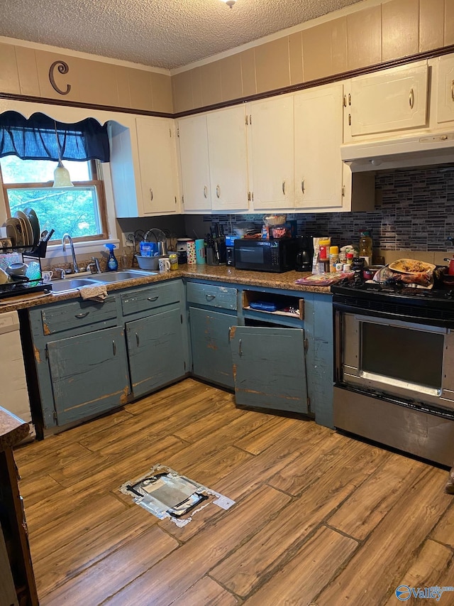 121 County Road 575, Rogersville, AL 35652 - kitchen with under cabinet range hood, a textured ceiling, gas stove, crown molding, and white cabinets