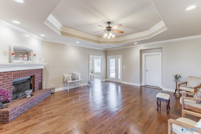 101 Tempo Cir, Harvest, AL 35749 - living area with a tray ceiling, a ceiling fan, wood finished floors, crown molding, and a brick fireplace