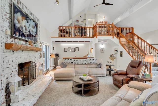 carpeted living area featuring beamed ceiling, a fireplace, a ceiling fan, high vaulted ceiling, and stairs