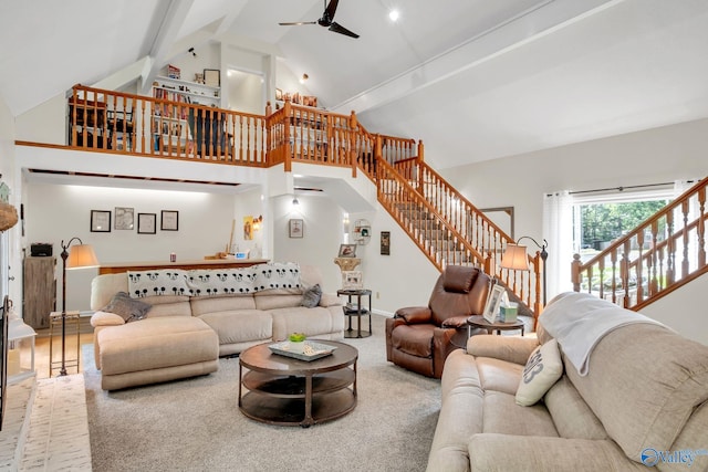 living room featuring beamed ceiling, ceiling fan, baseboards, stairway, and high vaulted ceiling