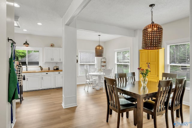 dining space featuring recessed lighting, a textured ceiling, light wood-style flooring, and baseboards