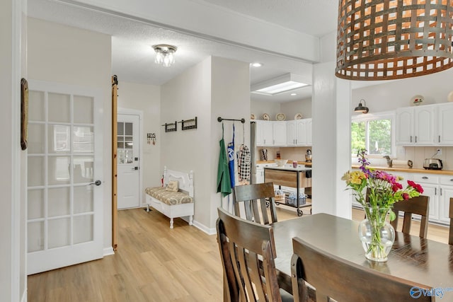 dining space with baseboards and light wood-style flooring