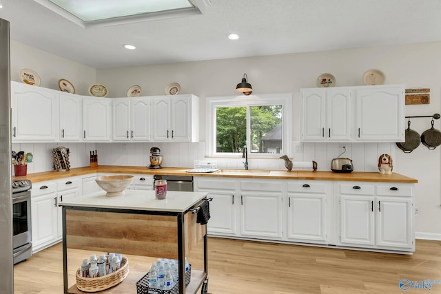 kitchen featuring stainless steel appliances, a sink, butcher block counters, and light wood-style floors