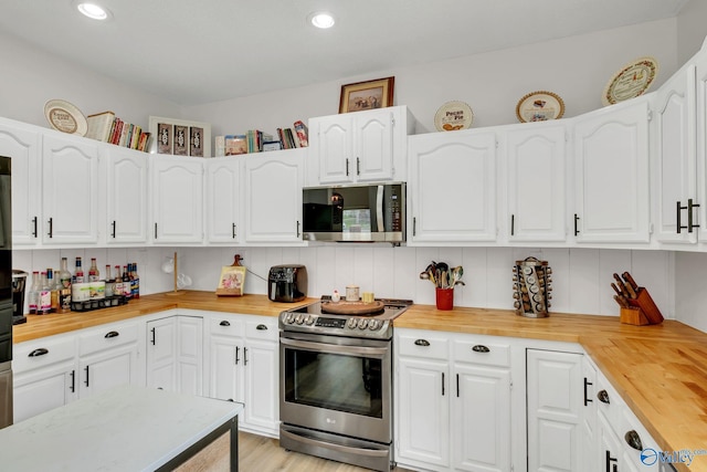 kitchen featuring recessed lighting, tasteful backsplash, appliances with stainless steel finishes, white cabinets, and wooden counters