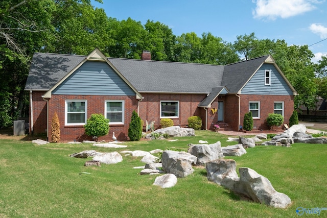view of front of property with a chimney, brick siding, a shingled roof, and a front yard