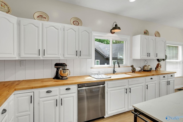 kitchen featuring a sink, backsplash, white cabinetry, stainless steel dishwasher, and wooden counters