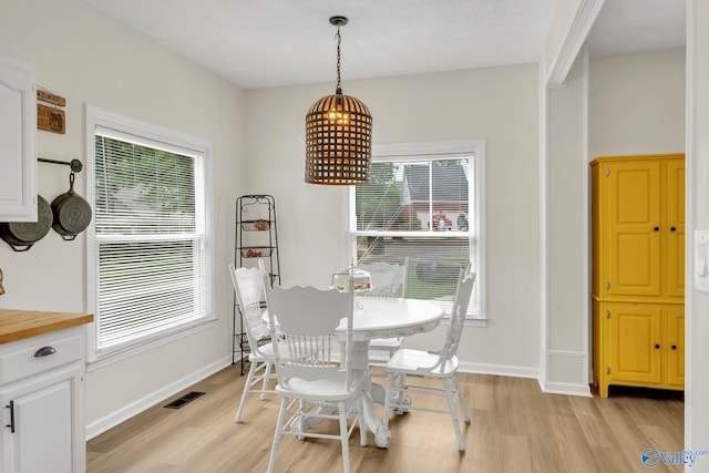 dining area with visible vents, light wood-style flooring, and baseboards