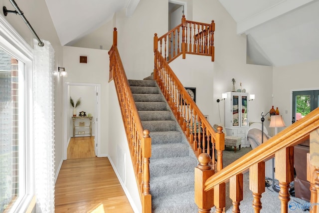 staircase featuring wood finished floors, high vaulted ceiling, and beamed ceiling