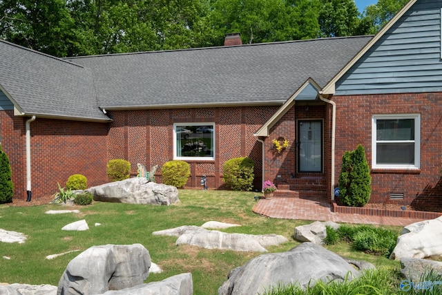 view of front of home with a front lawn, a chimney, entry steps, and brick siding