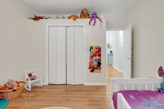 bedroom featuring a closet, light wood-style flooring, and baseboards