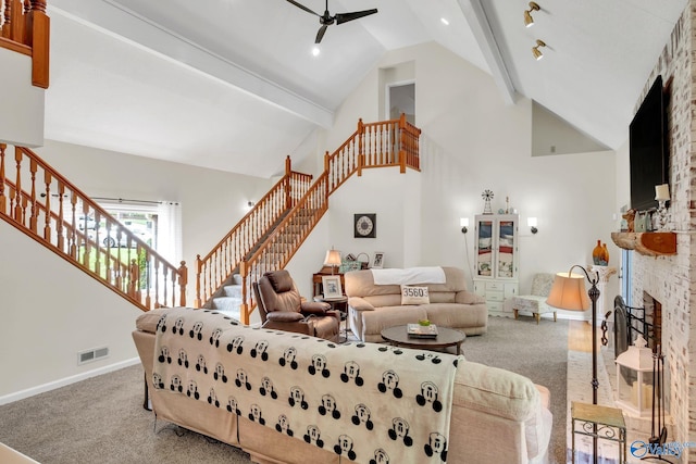 living room with beamed ceiling, a brick fireplace, stairs, a ceiling fan, and visible vents