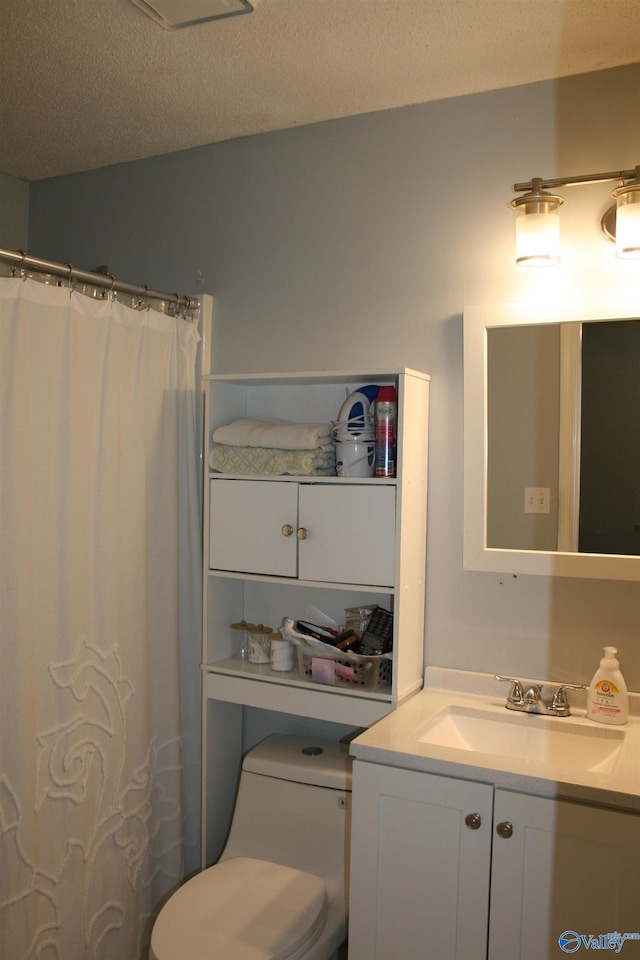 bathroom with vanity, toilet, curtained shower, and a textured ceiling