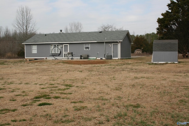 rear view of house with a yard, a patio area, central air condition unit, and a storage unit