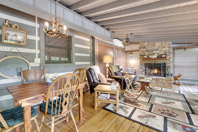 dining room with an AC wall unit, a chandelier, wood-type flooring, beam ceiling, and a fireplace