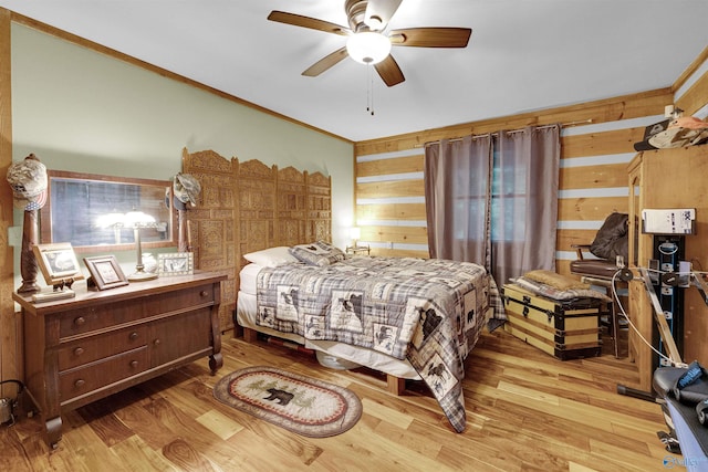 bedroom featuring ceiling fan, wooden walls, light hardwood / wood-style floors, and ornamental molding