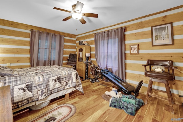 bedroom featuring hardwood / wood-style flooring, wooden walls, and ceiling fan