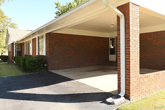 view of home's exterior with a carport, brick siding, and driveway