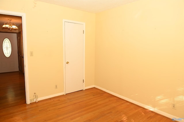 unfurnished room featuring light wood-type flooring, baseboards, and an inviting chandelier