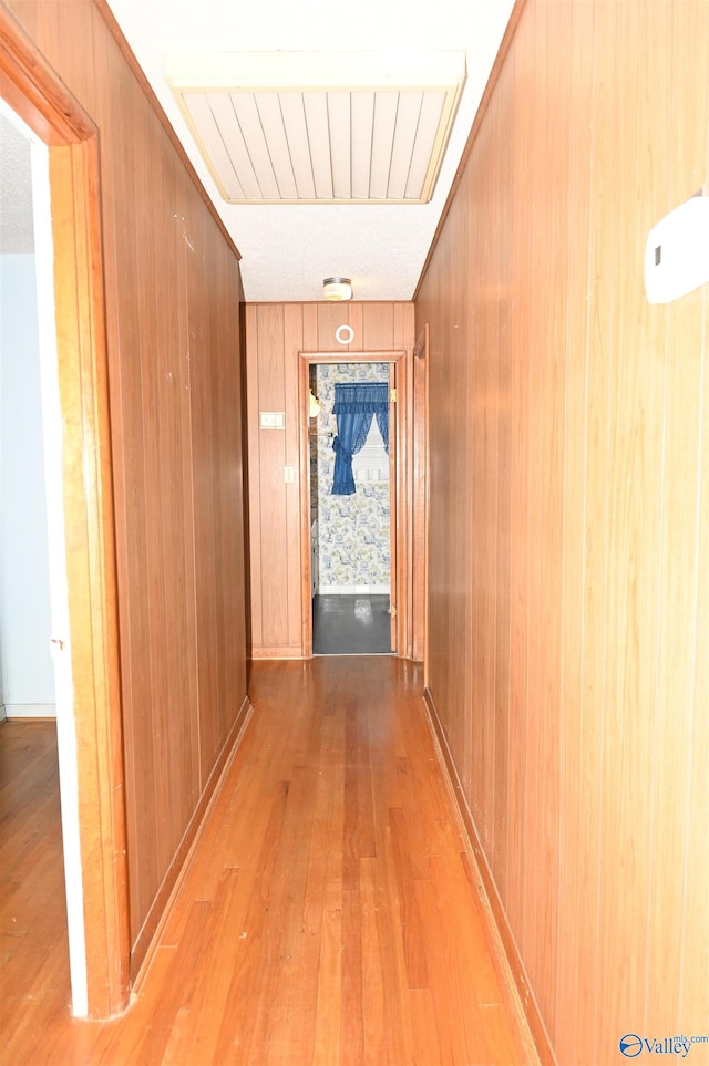 corridor featuring wood walls and light wood-type flooring