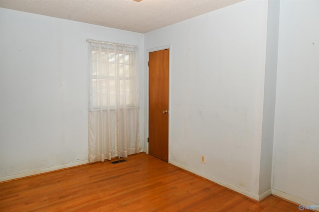 unfurnished room featuring baseboards, a textured ceiling, visible vents, and wood finished floors