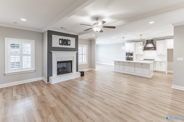 unfurnished living room with ceiling fan, ornamental molding, a fireplace, and light hardwood / wood-style floors