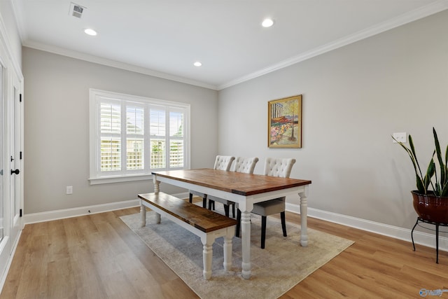 dining room with ornamental molding and light hardwood / wood-style floors